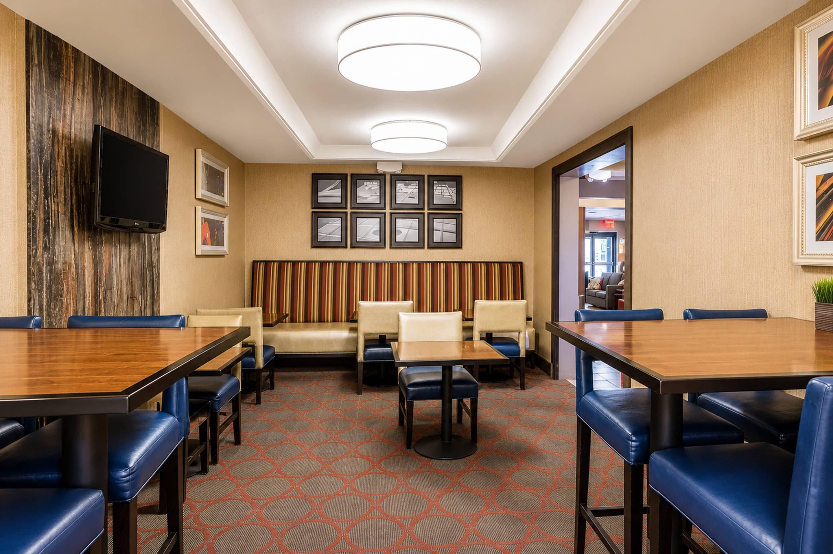 A hotel conference room with a long table, several chairs, a sofa, and a television on the wall.