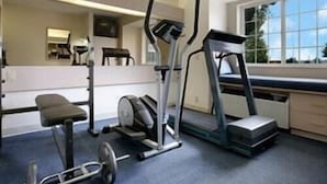 Un gimnasio en casa con cinta de correr, elíptica y banco de pesas.