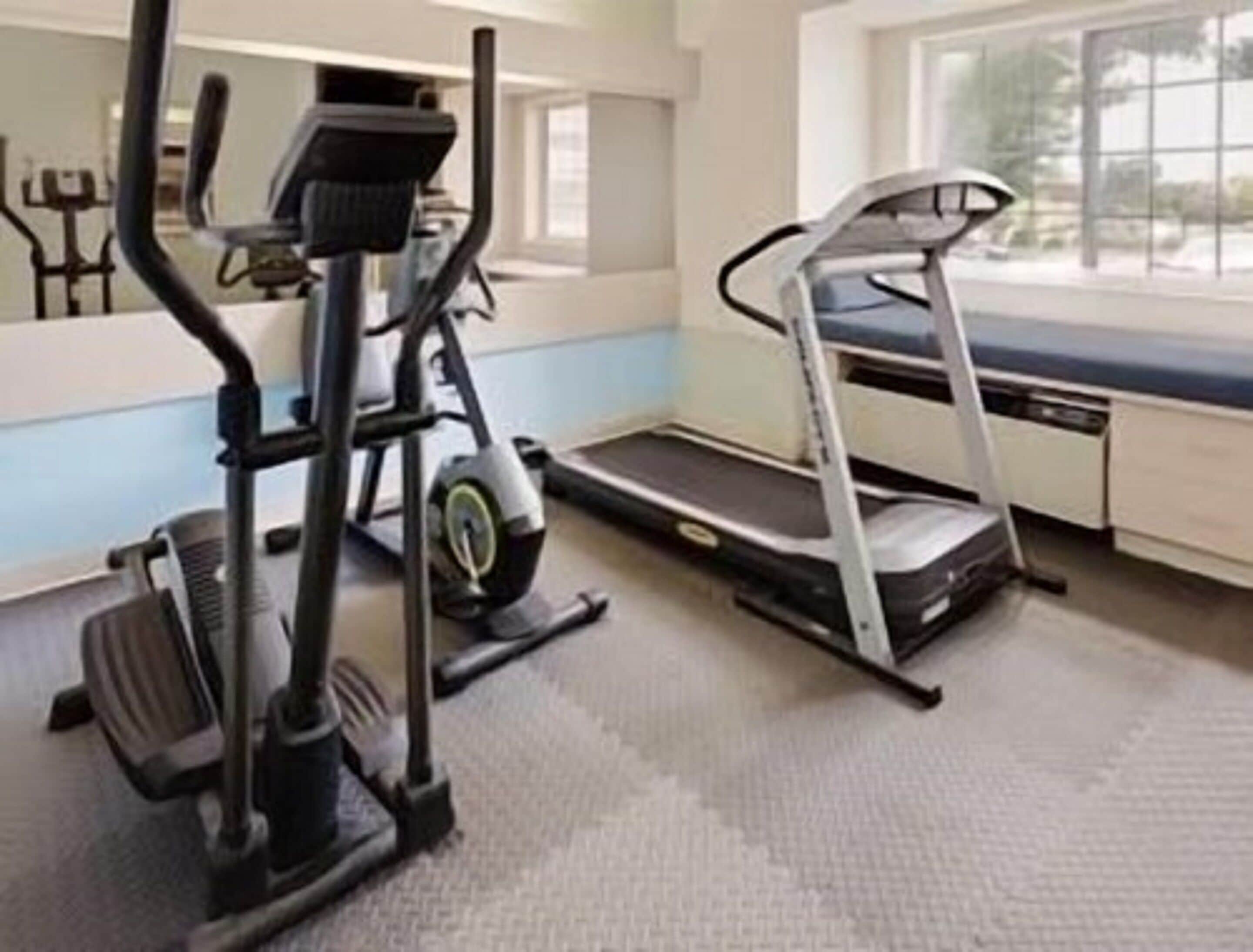 A gym with a treadmill, elliptical, and stationary bike.