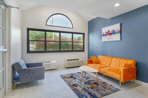 A modern living room with a large window, a sofa, a chair, and a small table. - Quality Inn Knoxville West Cedar Bluff (Knoxville)