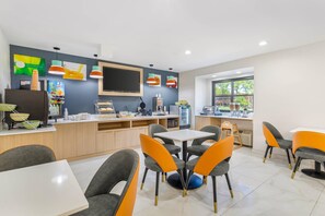 A modern kitchen with a flat-screen TV, a coffee machine, and a fruit dispenser. - Quality Inn Knoxville West Cedar Bluff (Knoxville)