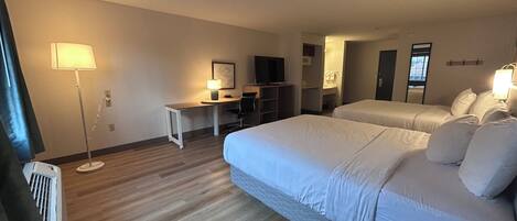 Une chambre d’hôtel avec deux lits, un bureau, une chaise, une lampe et un téléviseur.
