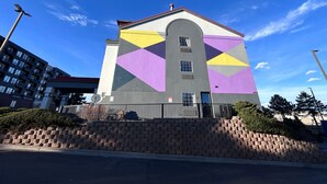 Un edificio con una fachada geométrica distintiva, una entrada destacada y una escalera de ladrillo que conduce a él.