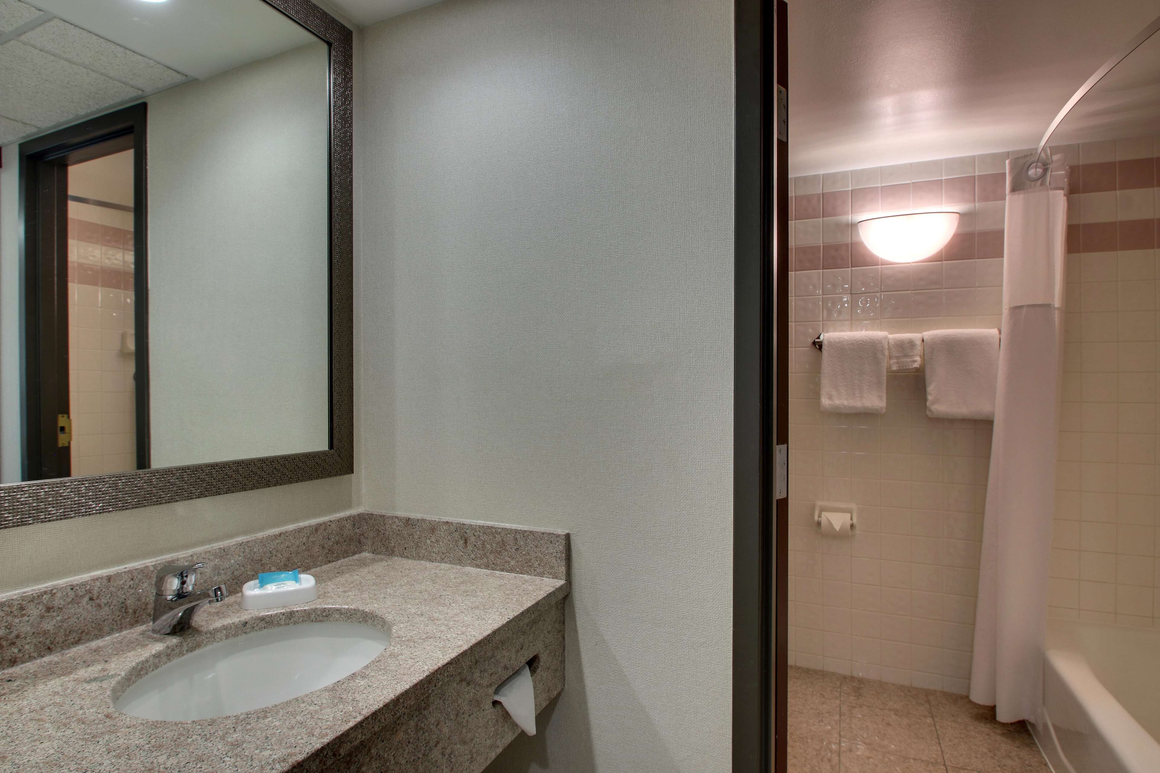 A bathroom with a sink, mirror, and shower area.