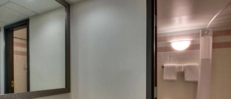 Un baño con lavamanos, espejo y zona de ducha.