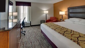 A hotel room with a bed, a desk, a chair, a TV, and a lamp. - Drury Inn & Suites Evansville East (Evansville)