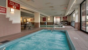 An indoor swimming pool with a capacity sign, a pool ladder, and a seating area with chairs. - Drury Inn & Suites Evansville East (Evansville)