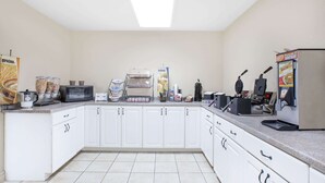 Eine Küche mit weißen Schränken, einer Mikrowelle, einer Kaffeemaschine und verschiedenen Geräten.