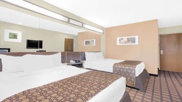 Habitación de hotel con dos camas, televisión, escritorio y puerta.