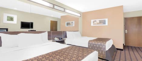 A hotel room with two beds, a TV, a desk, and a door.