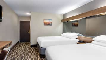 Une chambre d’hôtel avec deux lits, un bureau, une chaise, un téléphone et une porte.