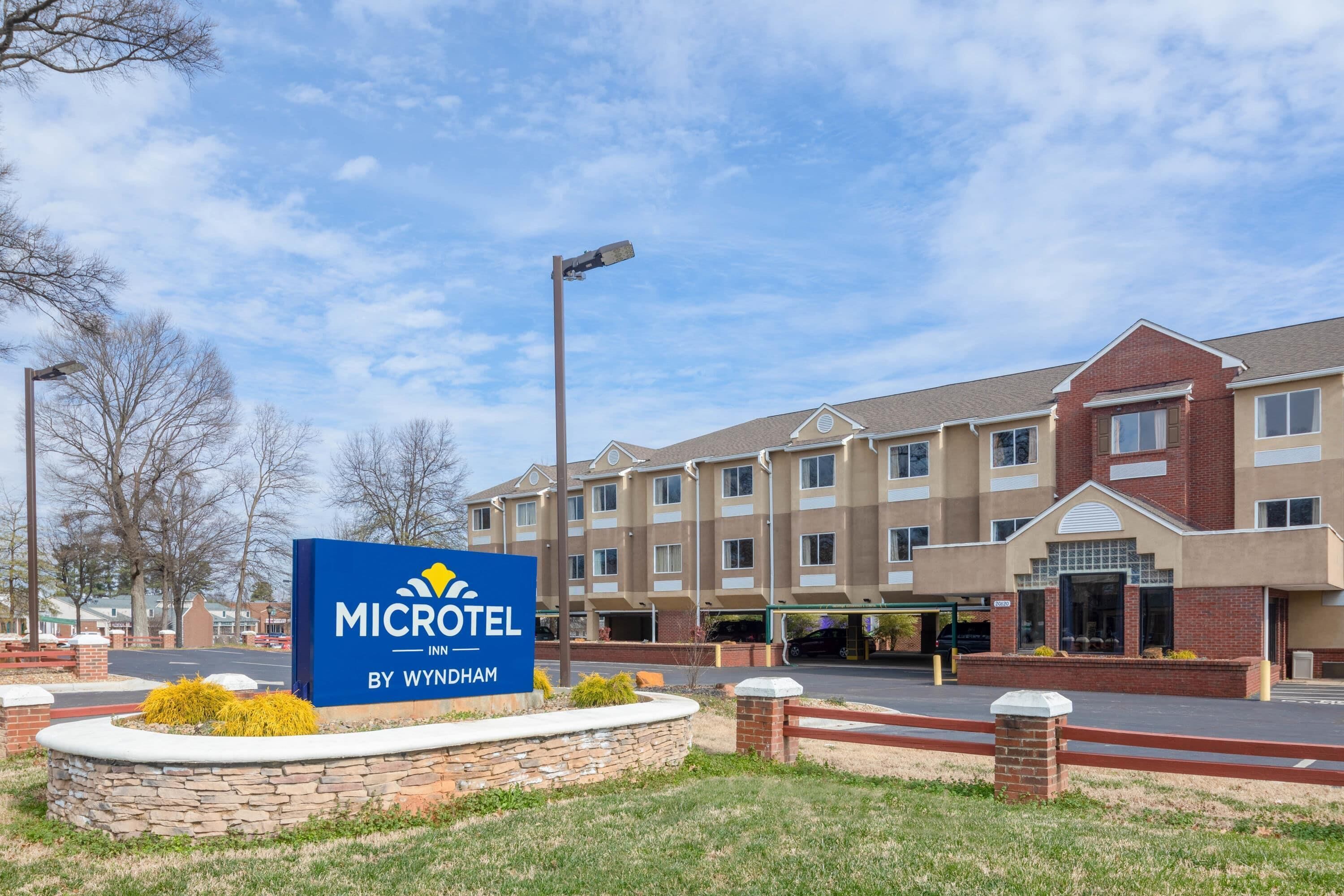 En Microtel Inn by Wyndham bygning med skilt, murstensfacade og parkeringsplads.