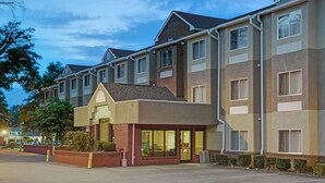 A multi-story hotel with a central entrance, large windows, and a parking lot. - Microtel Inn by Wyndham Cornelius/Lake Norman (Cornelius)