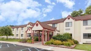 A hotel with a covered entrance, multiple windows, and a parking lot.