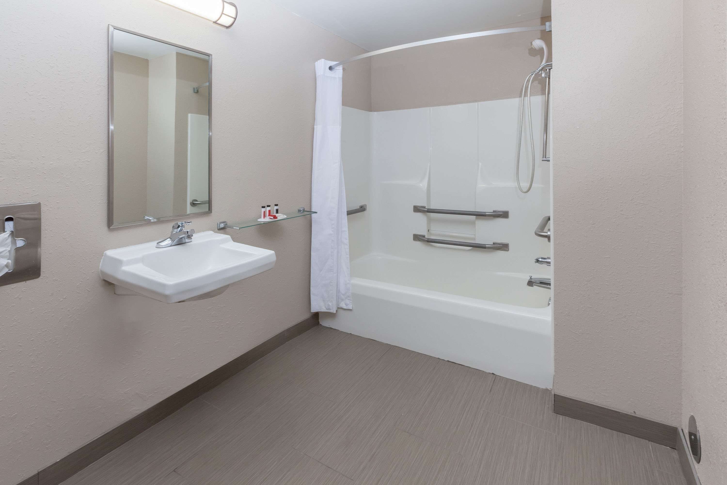 A modern bathroom with a white sink, mirror, and shower.