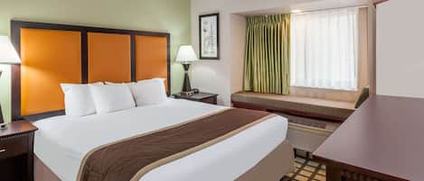 Habitación de hotel con una cama grande, una mesita de noche, cortinas y vistas al exterior.