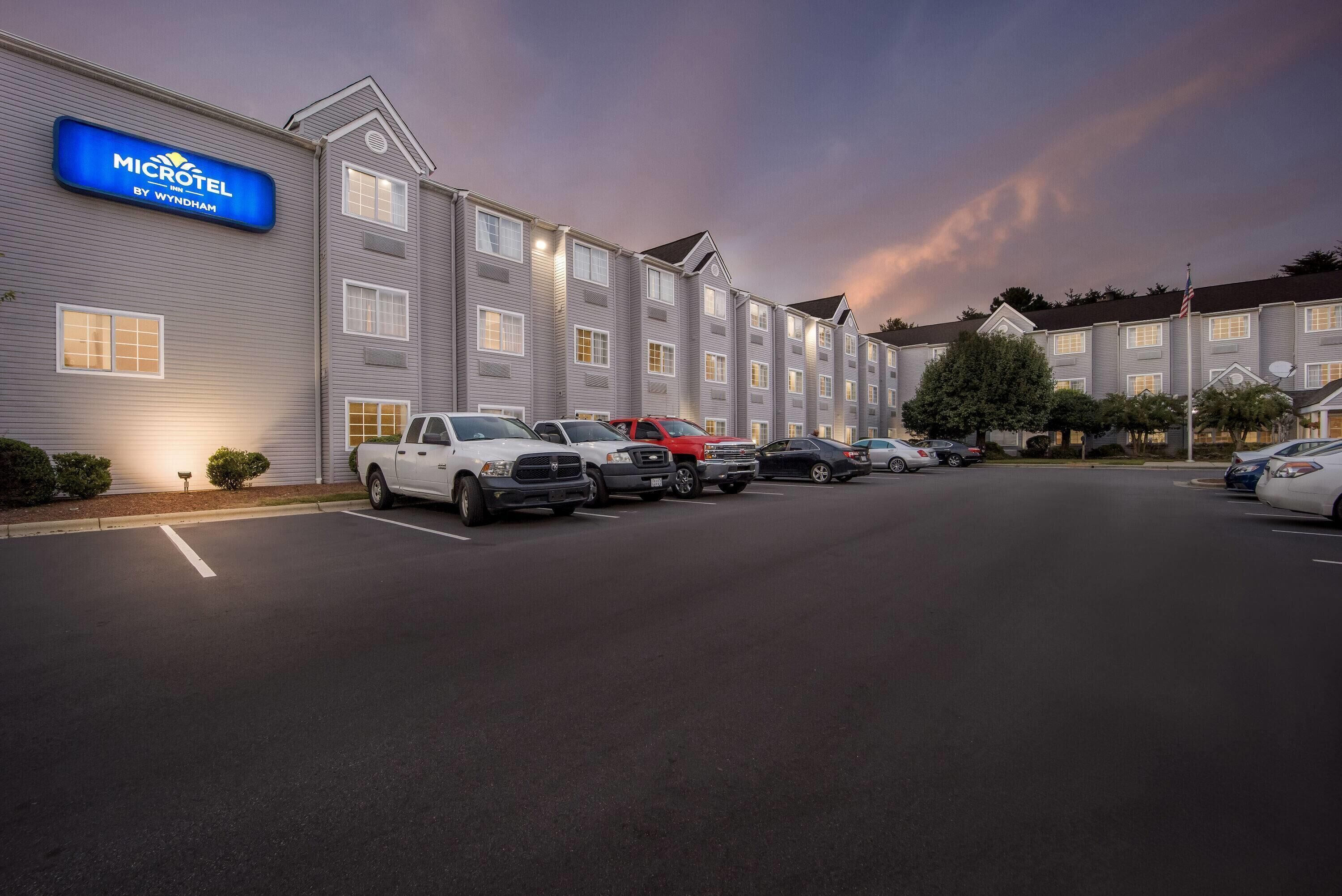 Un hotel Microtel con una fila de coches aparcados y fachada bien iluminada.