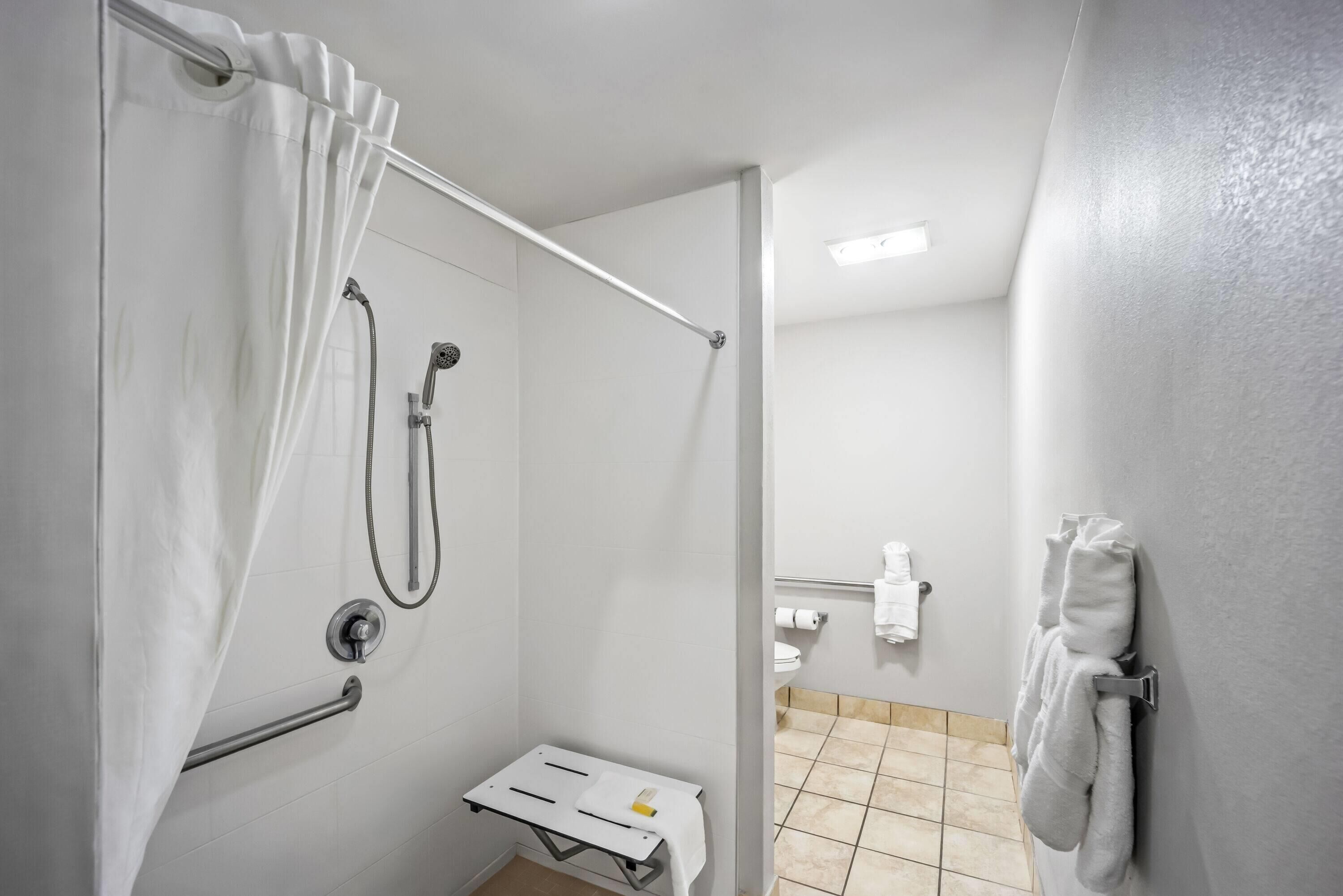 A modern bathroom with a shower, toilet, and towel rack.