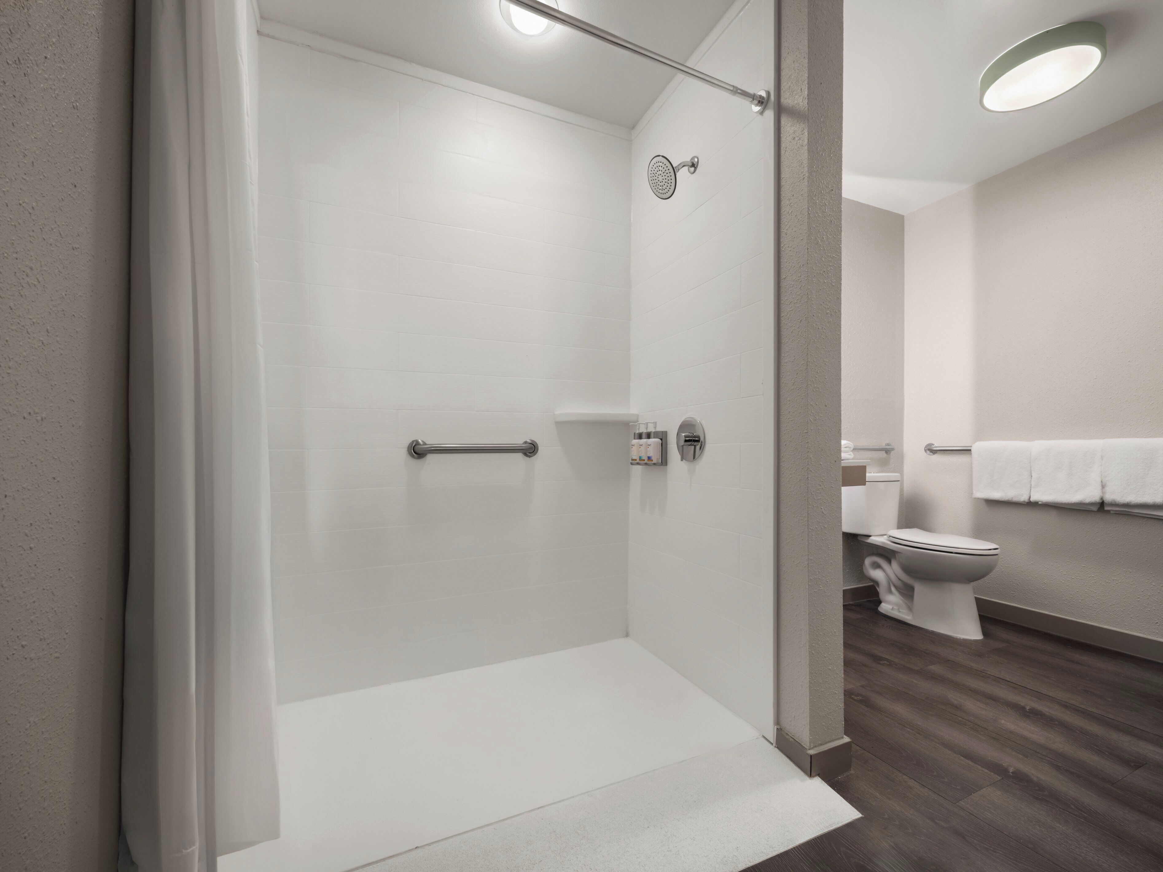 Ein modernes Badezimmer mit einer gläsernen Duschkabine, einer Toilette und einem Handtuchhalter.