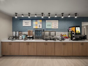A modern breakfast bar with a variety of food dispensers and a coffee machine. - Garner Hotel Greenville East by IHG (Greenville)