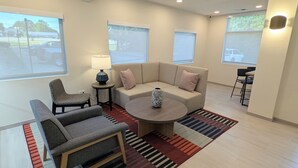 Een moderne woonkamer met een bank, fauteuils, een salontafel en een lamp.