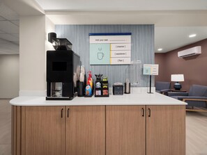 Un espace d’accueil équipé d’une machine à café, de produits de toilette et d’un panneau d’affichage.