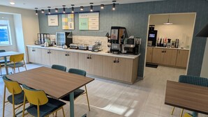 Een moderne keuken met een aanrecht, koffieapparaten en zitplaatsen.