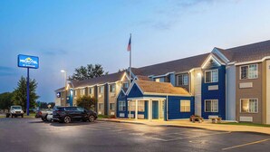 Un motel à la façade bleue, composé de plusieurs unités et doté d’un parking où sont garées des voitures.