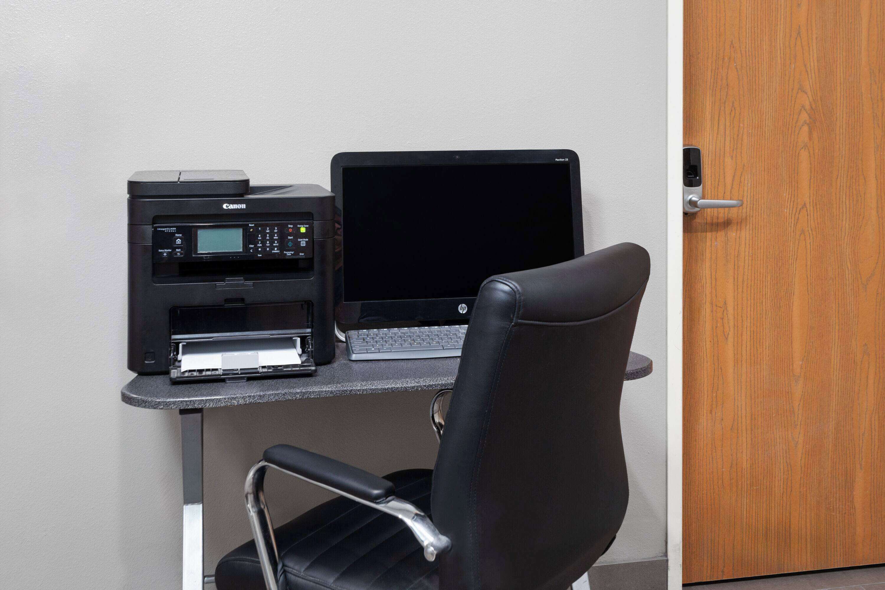 A workspace with a printer, laptop, and a chair.