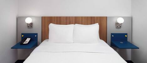 Quarto de hotel com cama, duas mesas de cabeceira e cabeceira de madeira.