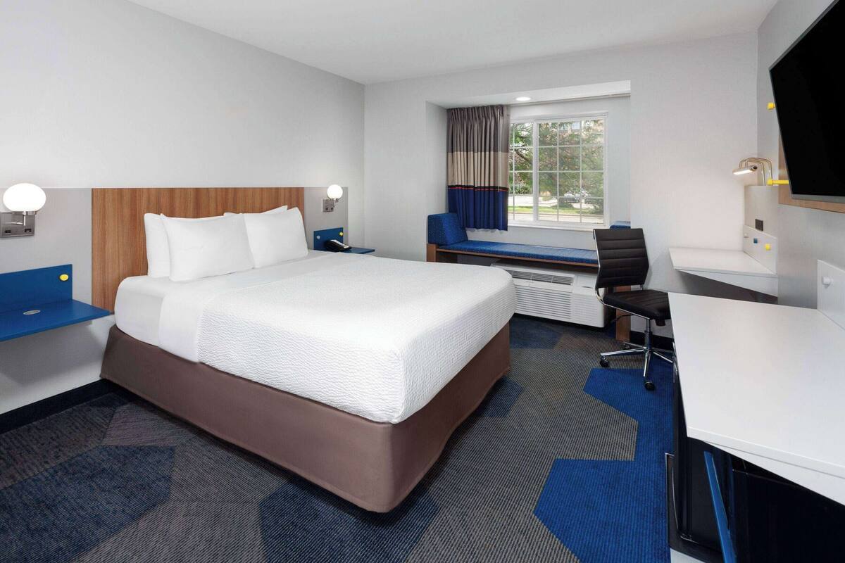 Una habitación de hotel con una cama grande, un escritorio, una silla y un televisor.