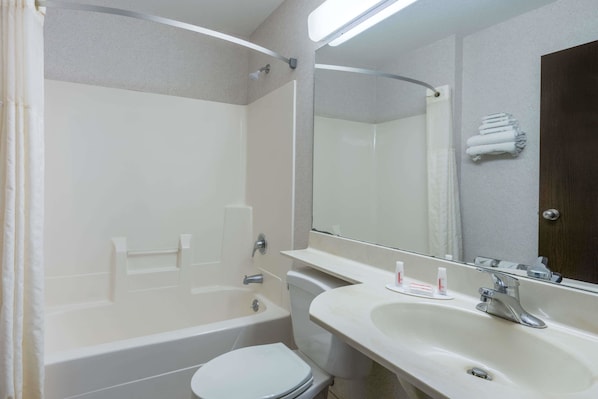 A bathroom with a bathtub, toilet, sink, and a mirror. - Microtel Inn by Wyndham Onalaska/La Crosse (Onalaska)