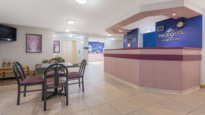 A reception area with a counter, chairs, a television, and a clock. - Microtel Inn by Wyndham Onalaska/La Crosse (Onalaska)