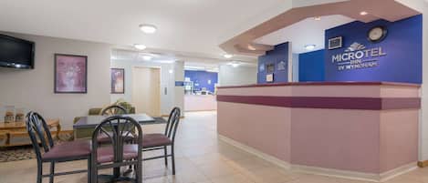 A reception area with a counter, chairs, a television, and a clock.