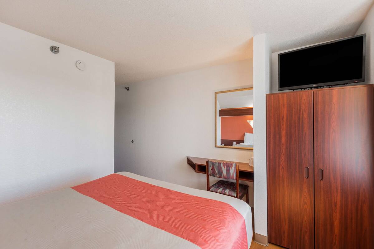 A hotel room with a bed, a desk, a television, and a wardrobe.