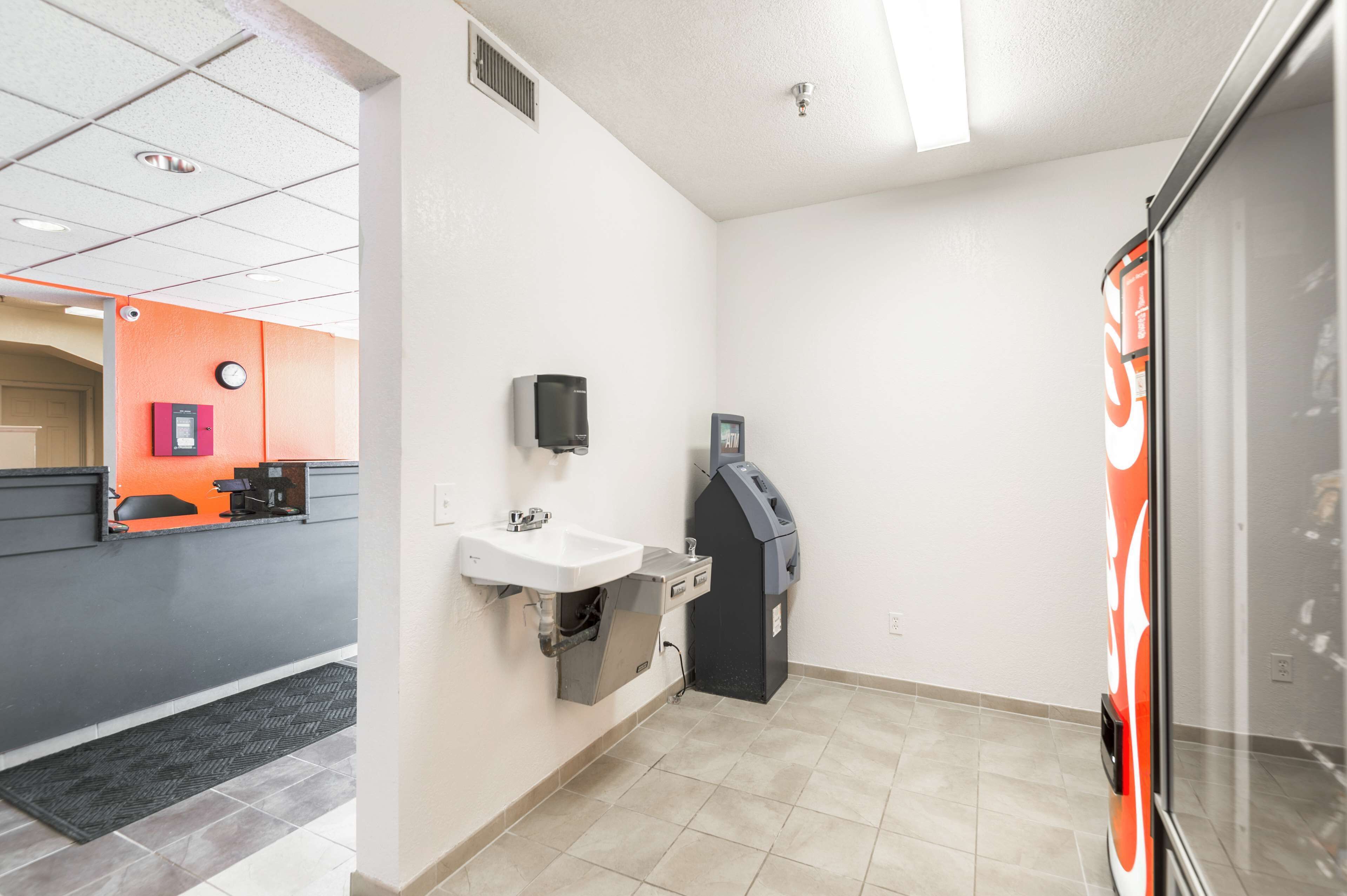 Un baño moderno y limpio con un lavabo, un bote de basura y una máquina expendedora de Coca-Cola.