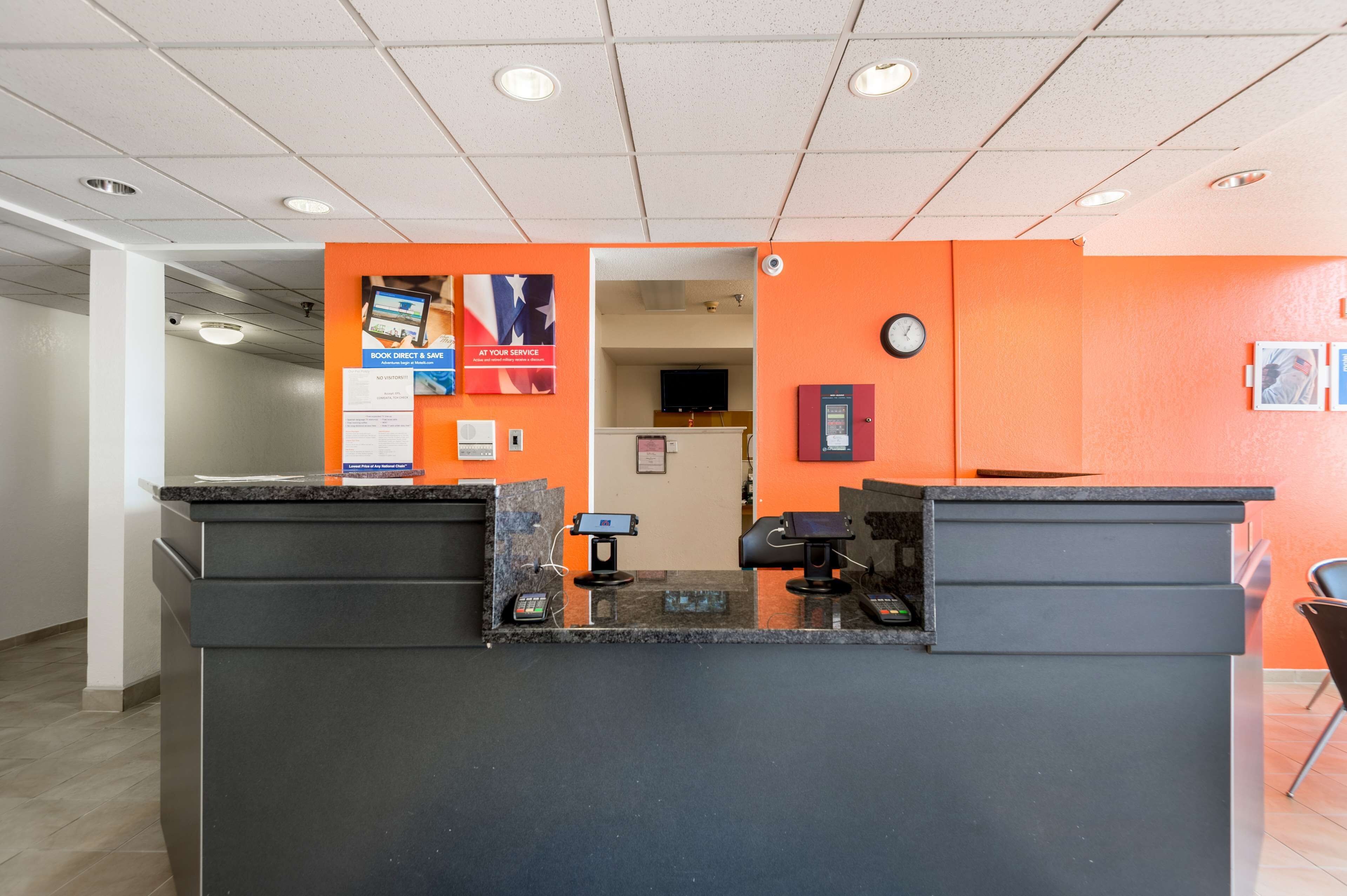 A reception area with a counter, a clock, and a poster on the wall.