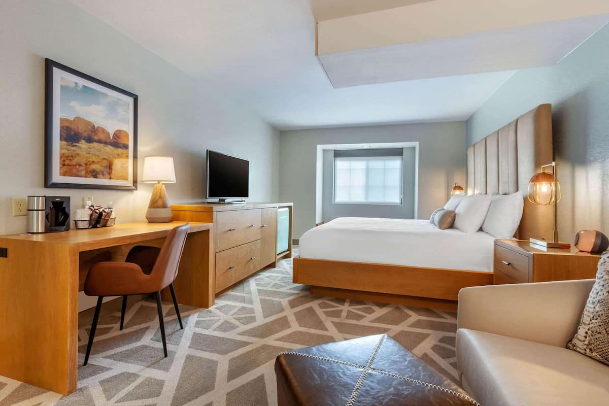 A hotel room with a bed, desk, chair, and a television.