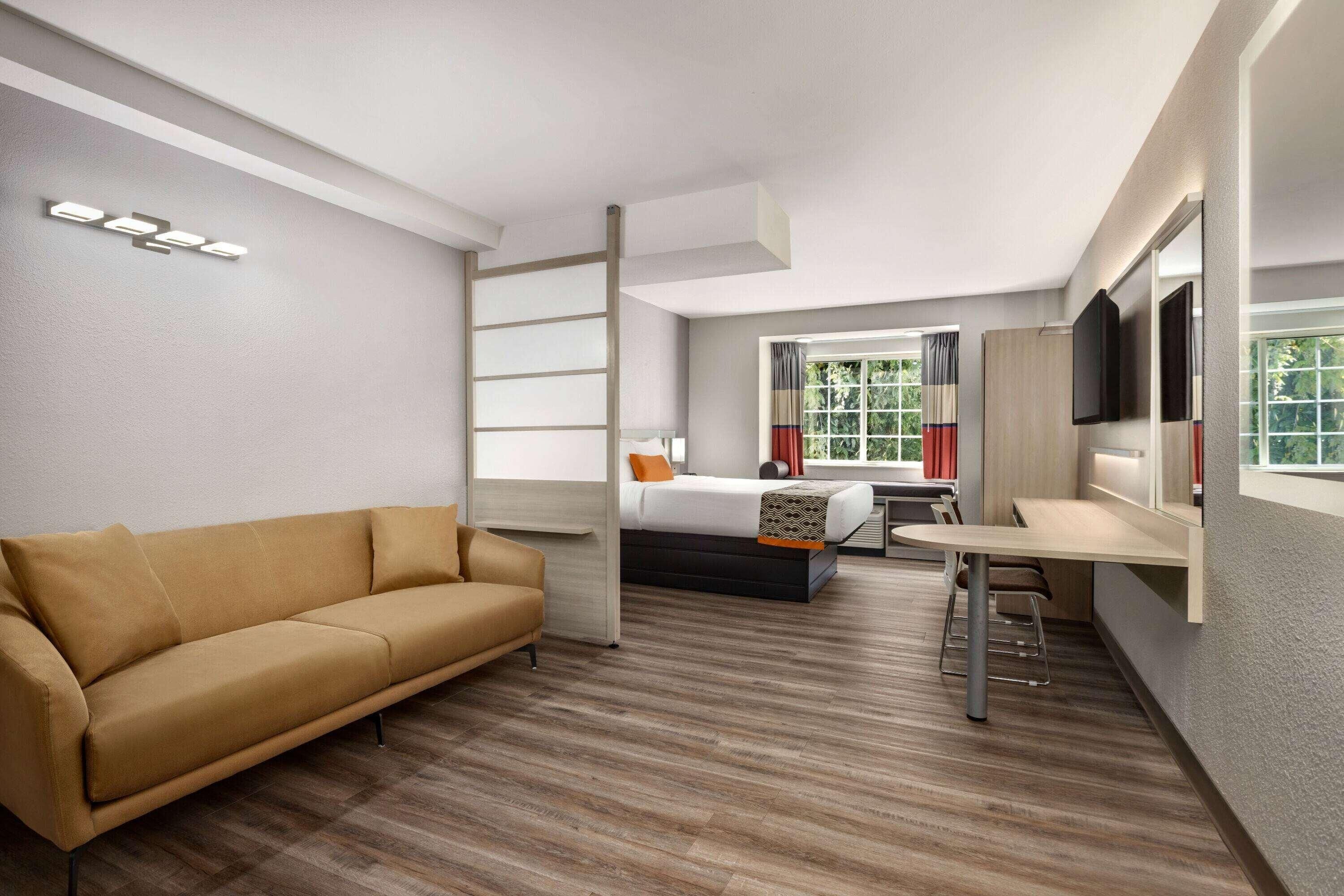 Una habitación de hotel moderna con sofá, cama, escritorio y televisor.