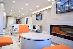 Un moderno vestíbulo de hotel con una recepción, zona de estar y una pantalla grande que muestra un edificio.