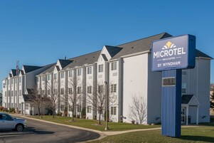 Edificio de Microtel Inn & Suites con un letrero, un estacionamiento y un cielo despejado.