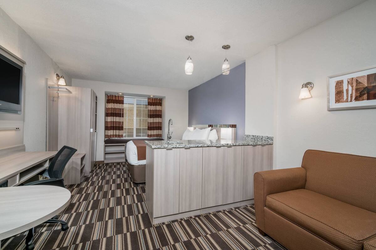 Une chambre d’hôtel compacte comprenant un coin cuisine, un espace repas, un canapé et un lit.