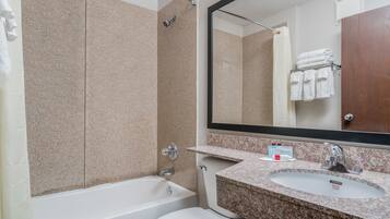 Un baño con bañera, inodoro, lavabo y un espejo grande.