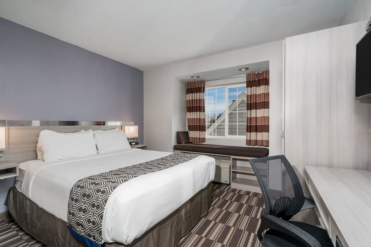 Une chambre d’hôtel équipée d’un lit, d’un bureau, d’une chaise et d’un téléviseur.