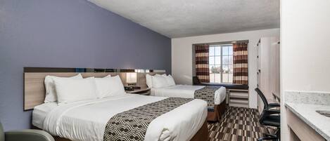 Une chambre d’hôtel avec deux lits, un bureau, une chaise et une fenêtre avec des rideaux.