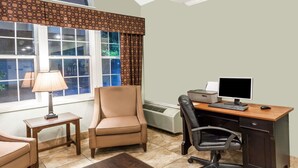 A room with a desk, computer, chair, and a window with curtains.