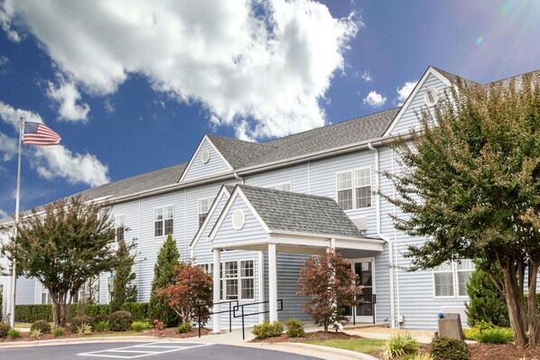 Stunning two-story building with a symmetrical facade and covered porch, set amidst beautifully maintained grounds.