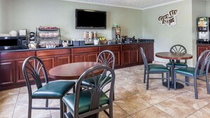 A kitchen with a dining area, equipped with a microwave, coffee maker, and a flat-screen TV.