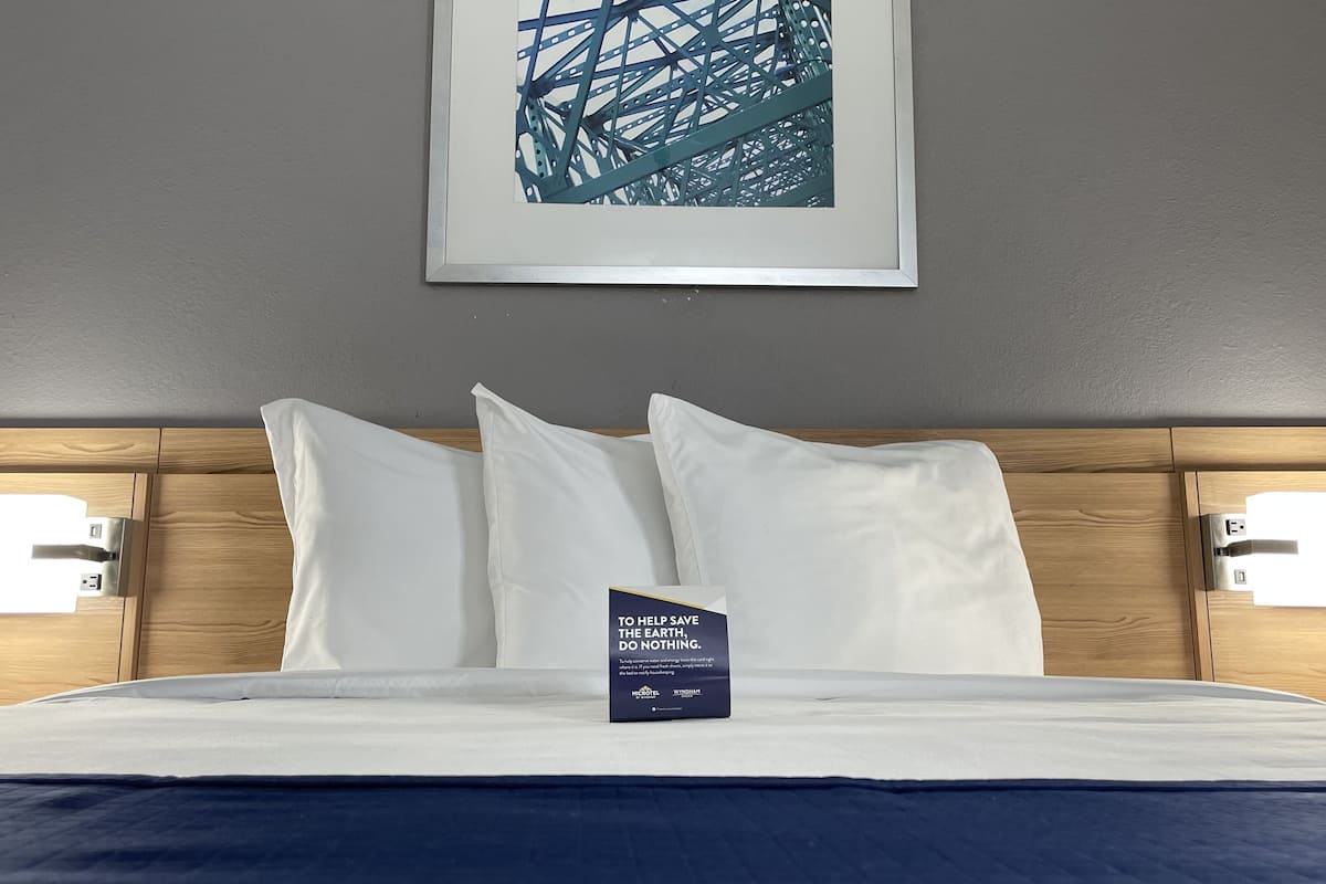 A neatly made bed with white linens, two bedside lamps, and a framed picture on the wall.
