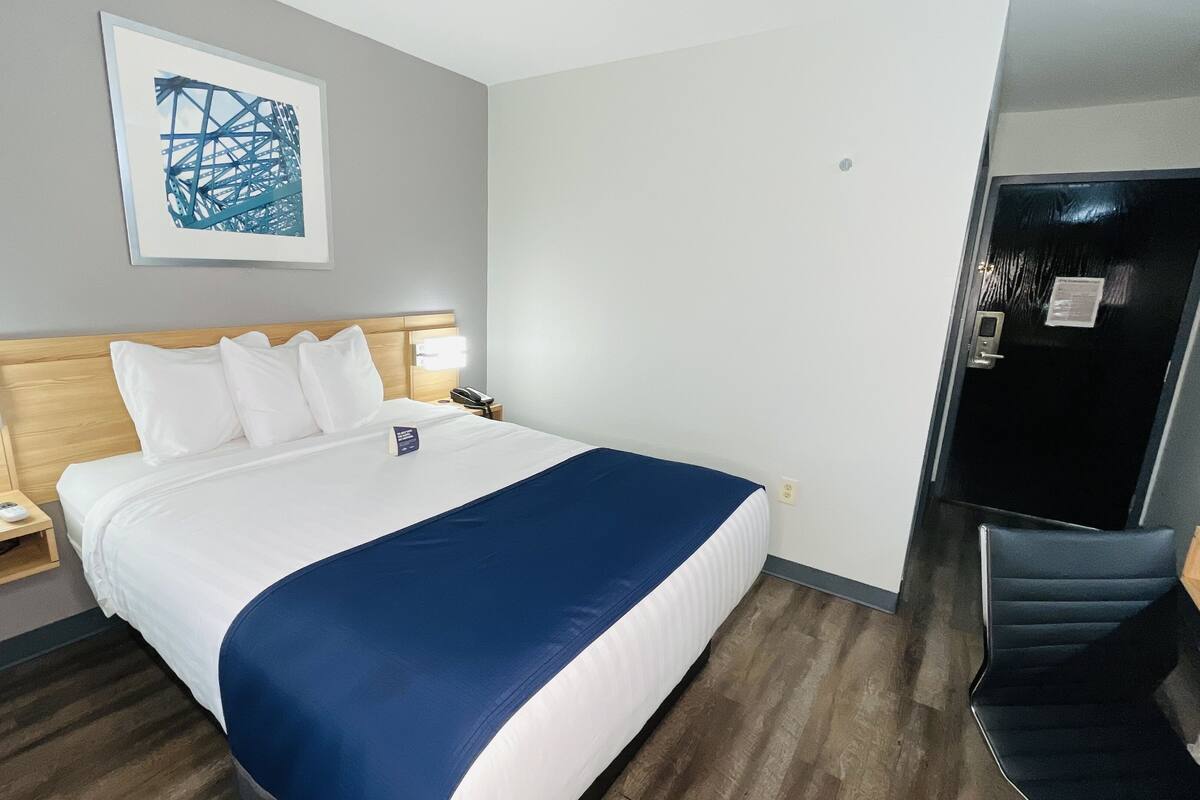 A hotel room with a bed, bedside tables, a desk, and a chair.